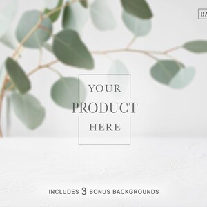 Könnte beinhalten: Minimalistischer Produktfotografie-Hintergrund mit weißer Oberfläche und verschwommenem Eukalyptuszweig. Der Text "YOUR PRODUCT HERE" ist zentriert, mit "INCLUDES 3 BONUS BACKGROUNDS" unten. Das Logo von The Background Company befindet sich oben rechts.