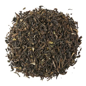 May include: A close-up of a pile of loose leaf black tea. The tea leaves are dark brown and have a slightly green hue. The leaves are dry and appear to be ready for brewing.