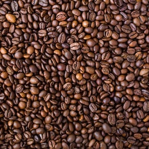 May include: A close-up image of a large quantity of roasted coffee beans. The beans are dark brown and have a slightly oily sheen.