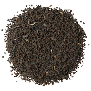 May include: A close-up of a pile of loose leaf black tea with small pieces of tea leaves and some larger pieces of tea leaves.