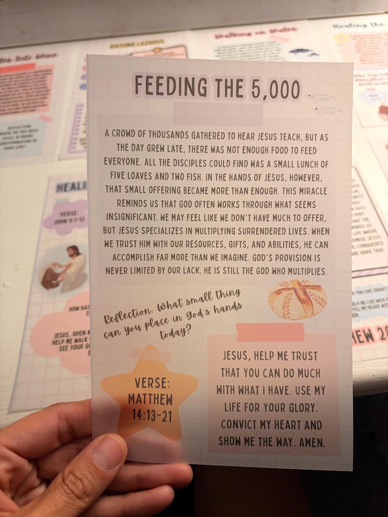 Może przedstawiać: Prostokątna karta dewocyjna zatytułowana Feeding the 5,000 z tłem w kratkę. Zawiera czarny tekst opisujący biblijny cud, małą ilustrację chleba, brzoskwiniową gwiazdę z napisem Matthew 14:13-21 oraz modlitwę.