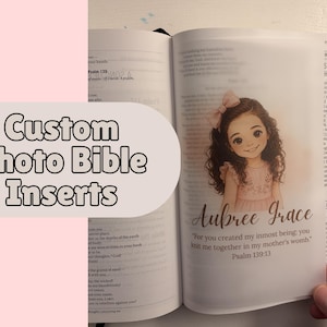 May include: Open Bible with a custom photo insert featuring a watercolor illustration of a girl with a pink bow. The insert includes the name "Aubree Grace" and a Bible verse. The text "Custom Photo Bible Inserts" is displayed.