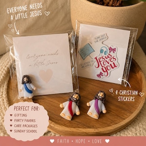 May include: Three small Jesus figurines with brown hair and beards, wearing white robes with blue, red, or purple sashes. Two figurines are loose, and one is packaged with a card reading Everyone needs a little Jesus. Includes a sticker sheet.