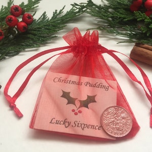 May include: A red mesh bag containing a pink card that reads "Christmas Pudding Lucky Sixpence" and a copper-coloured coin.