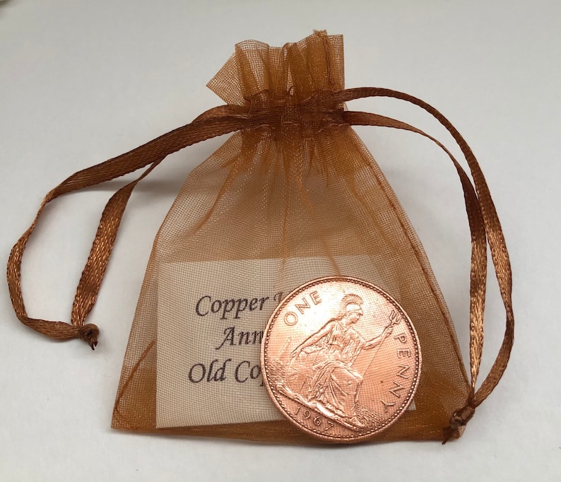 May include: A copper one penny coin from 1967 in a brown organza bag with a tag that reads "Copper 1st Anniversary Old Coin".