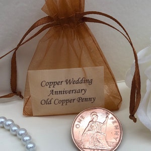 May include: A brown organza bag with a white card that reads "Copper Wedding Anniversary Old Copper Penny". A copper penny from 1967 is visible in the bag.