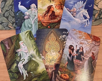 Op de afbeelding: Een tarotkaartleessespreiding met zes kaarten die op een tafel liggen. De kaarten zijn uit het "The Wild Unknown Tarot" deck. De kaarten zijn: Koningin van Bekers, Vijf van Pentakels, Drie van Bekers, De Geliefden, De Wereld en De Wagen.