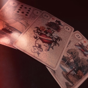 Puede incluir: Tres cartas de tarot con ilustraciones ornamentadas se muestran sobre un fondo oscuro. Las cartas presentan imágenes de un barco, un jarrón en forma de corazón con flores y una figura en un jardín. Las cartas tienen los números 3, 24 y 22.