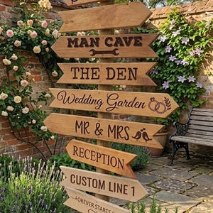 May include: A wooden directional signpost featuring multiple arrow-shaped planks with engraved text including BEER GARDEN, BREW HOUSE, MAN CAVE, THE DEN, Wedding Garden, MR & MRS, RECEPTION, CUSTOM LINE 1, FOREVER STARTS HERE, and OCT 26, 2024.