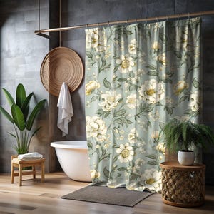 May include: A shower curtain with a floral pattern featuring white flowers and green leaves on a light blue background.