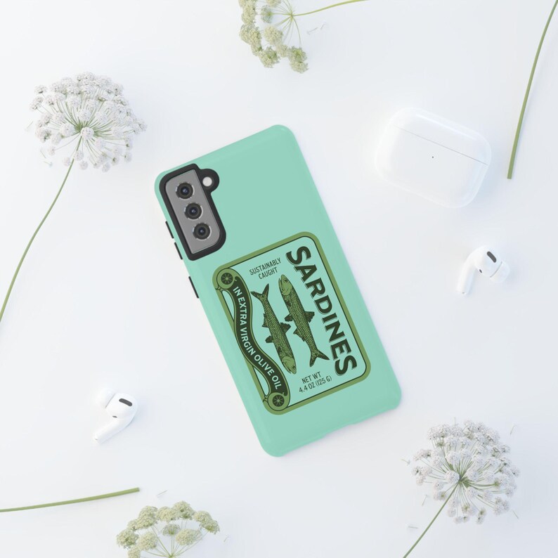 Peut inclure: Une coque de t&eacute;l&eacute;phone vert menthe avec un design de bo&icirc;te de sardines vintage. La bo&icirc;te indique "Sardines" en caract&egrave;res gras et repr&eacute;sente deux sardines conserv&eacute;es dans de l'huile d'olive extra vierge. Le texte indique &eacute;galement "P&ecirc;che durable" et "Poids net 4,4 oz (125 g)".