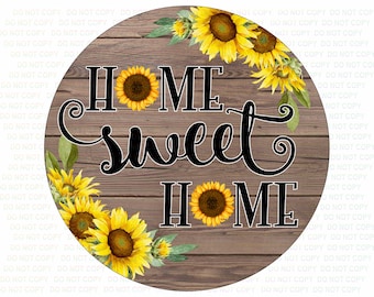 May include: A round wooden sign with a brown woodgrain background and a wreath of sunflowers around the edge. The sign says "Home Sweet Home" in black cursive lettering.