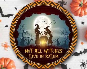 May include: A round, orange and black Halloween-themed sign with a chevron pattern border. The sign features a silhouette of two witches stirring a cauldron under a full moon. The text on the sign reads "Not All Witches Live In Salem".
