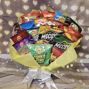 May include: A bouquet of various flavored potato chips wrapped in yellow and white tissue paper with white polka dots. The bouquet is tied with a white satin ribbon.
