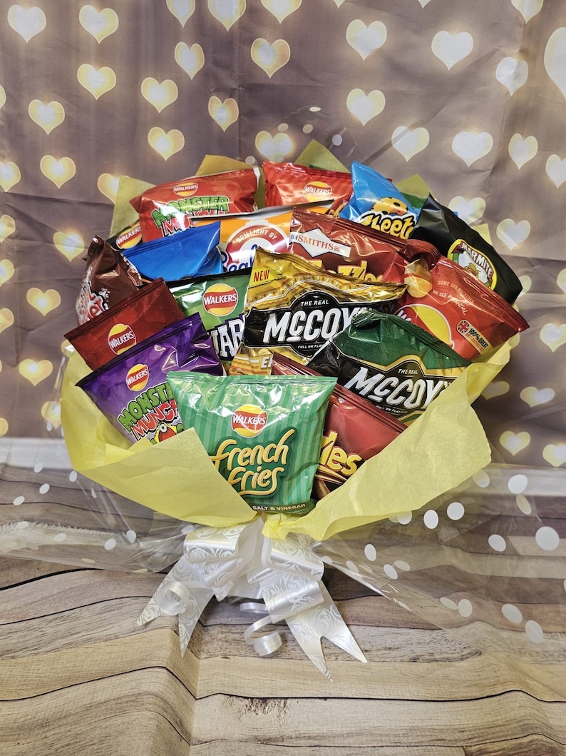 May include: A bouquet of various flavored potato chips wrapped in yellow and white tissue paper with white polka dots. The bouquet is tied with a white satin ribbon.