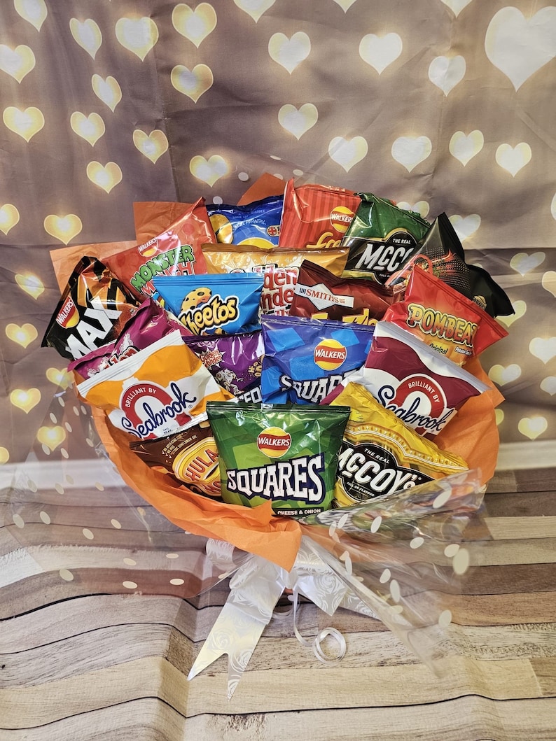 May include: A bouquet of various chip bags, including Seabrook, McCoy's, Monster Munch, Walkers Squares, and Walkers Cheese & Onion. The bouquet is wrapped in orange tissue paper and clear cellophane.