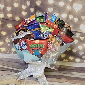 May include: A bouquet of various snack chips and crisps, including Seabrook, Monster Munch, and Cheetos, arranged in a clear plastic wrap with a white ribbon.