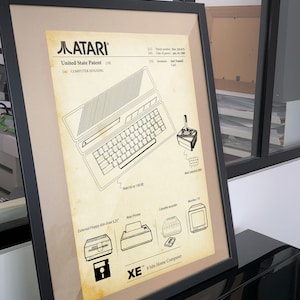 Op de afbeelding: Een zwart-witte lijntekening van de Atari XE 8-bits thuiscomputer. De tekening omvat de behuizing van de computer, het toetsenbord, de joystick en de externe randapparatuur. De tekst "Atari XE 8-bit Home Computer" is onder de tekening afgedrukt.