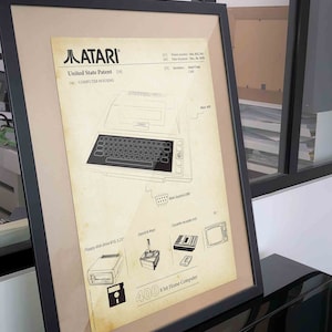Op de afbeelding: Een vintage-stijl illustratie van de Atari 400 homecomputer, een patenttekening uit 1979. De illustratie toont het ontwerp van de computer, inclusief het toetsenbord, het floppy disk-station en de joystick. De tekst "Atari 400 8 bit Home Computer" is onder de illustratie afgedrukt.