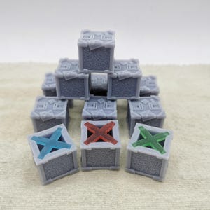 Può includere: Una pila di scatole grigie, testurizzate, a forma di cubo con X di diversi colori sulla parte superiore. Le scatole sono disposte a forma di piramide.