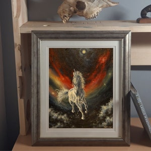 May include: A framed painting of a white unicorn galloping through a starry sky with a red and orange nebula in the background.