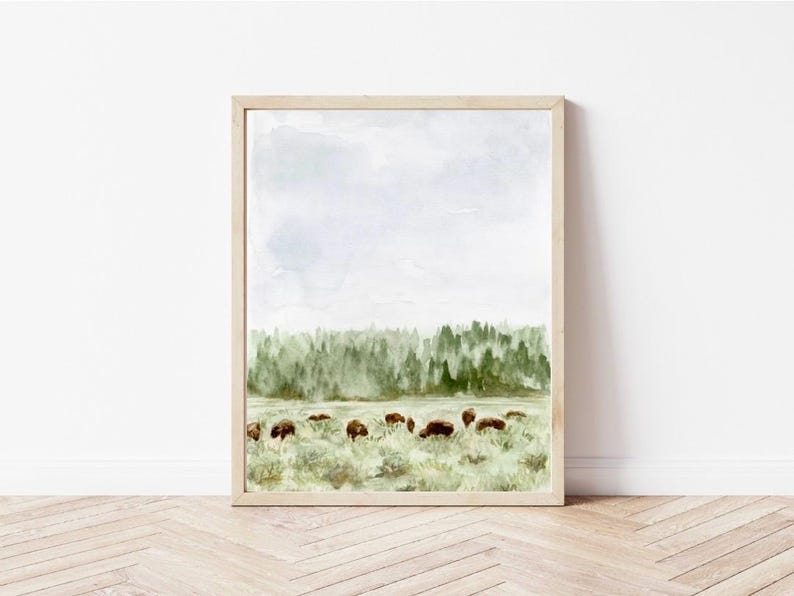May include: Watercolor painting of a forest landscape with a herd of bison grazing in a field. The sky is a light blue with white clouds. The trees are a dark green and the grass is a light green.