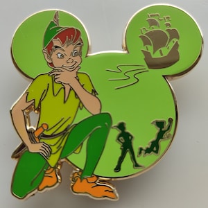 Peut inclure: Épingle sur le thème de Peter Pan en forme d'oreilles de Mickey Mouse. L'épingle représente Peter Pan en tenue verte, un navire et des silhouettes d'autres personnages. L'épingle a une bordure dorée et un fond vert clair.