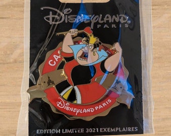 May include: A Disneyland Paris pin featuring the Queen of Hearts from Alice in Wonderland. The pin is in a clear plastic package with a black backing. The pin has a red and gold color scheme and the text "Disneyland Paris" is visible.