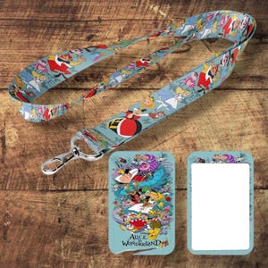 Op de afbeelding: Een lichtblauwe lanyard met personages uit Alice in Wonderland, met een zilverkleurige sluiting. Inclusief een bijpassende kaarthouder met de tekst "Alice Wonderland". De lanyard en kaarthouder hebben een herhalend patroon van personages.