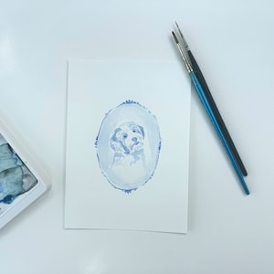 May include: A watercolor painting of a dog's head in a blue oval frame. The dog is white with a light blue background.