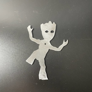 Könnte beinhalten: Ein Metallausschnitt einer fiktiven Figur, Groot, aus dem Marvel Cinematic Universe. Der Ausschnitt steht mit ausgestreckten Armen.