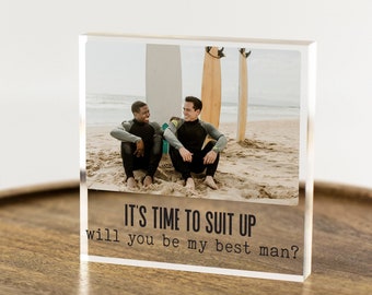May include: A clear acrylic block with a photo of two people sitting on a beach with surfboards behind them. The text "IT'S TIME TO SUIT UP will you be my best man?" is printed on the block.