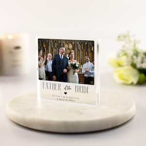 May include: A clear acrylic photo block with a photo of a wedding ceremony. The text "FATHER of the BRIDE" is printed on the block, along with the quote "All that I am or hope to be, I owe to my father."