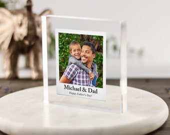 Puede incluir: Un bloque de foto de acrílico transparente con una imagen de un padre y un hijo sonriendo. El texto "Michael & Dad Happy Father's Day!" está impreso en el bloque.