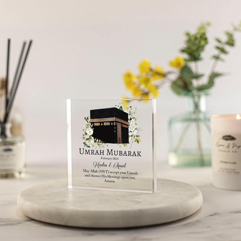 Pu&ograve; includere: Un blocco di acrilico trasparente con un'immagine stampata della Kaaba, un design floreale e il testo "Umrah Mubarak, febbraio 2024, Nadia & Amal, Che Allah (SWT) accetti la tua Umrah e ti conceda le Sue benedizioni. Amen."
