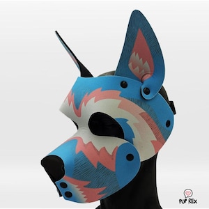 Può includere: Un muso per cani con motivo blu e rosa, con naso nero e cinturini regolabili. Il muso è realizzato in materiale morbido e flessibile e ha un design unico.