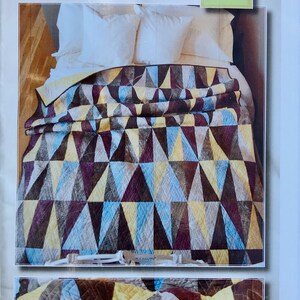 May include: A quilt pattern called "Backgammon in Plaster" designed by Mary Patterson. The quilt is made of geometric shapes in shades of brown, yellow, blue, and purple. The finished size is 56 inches by 74 inches.