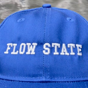 May include: A blue baseball cap with white embroidered text that reads "FLOW STATE".