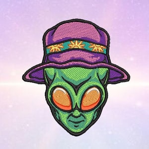 Può includere: Alieno verde con un cappello a secchiello viola e turchese con un design a sole giallo. L'alieno ha grandi occhi arancioni e un viso verde.