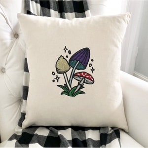 Magical mushroom cluster embroidery file in a fantasy fairy garden. Cute mushrooms from a magical garden. Shown embroidered into a pillow cover.