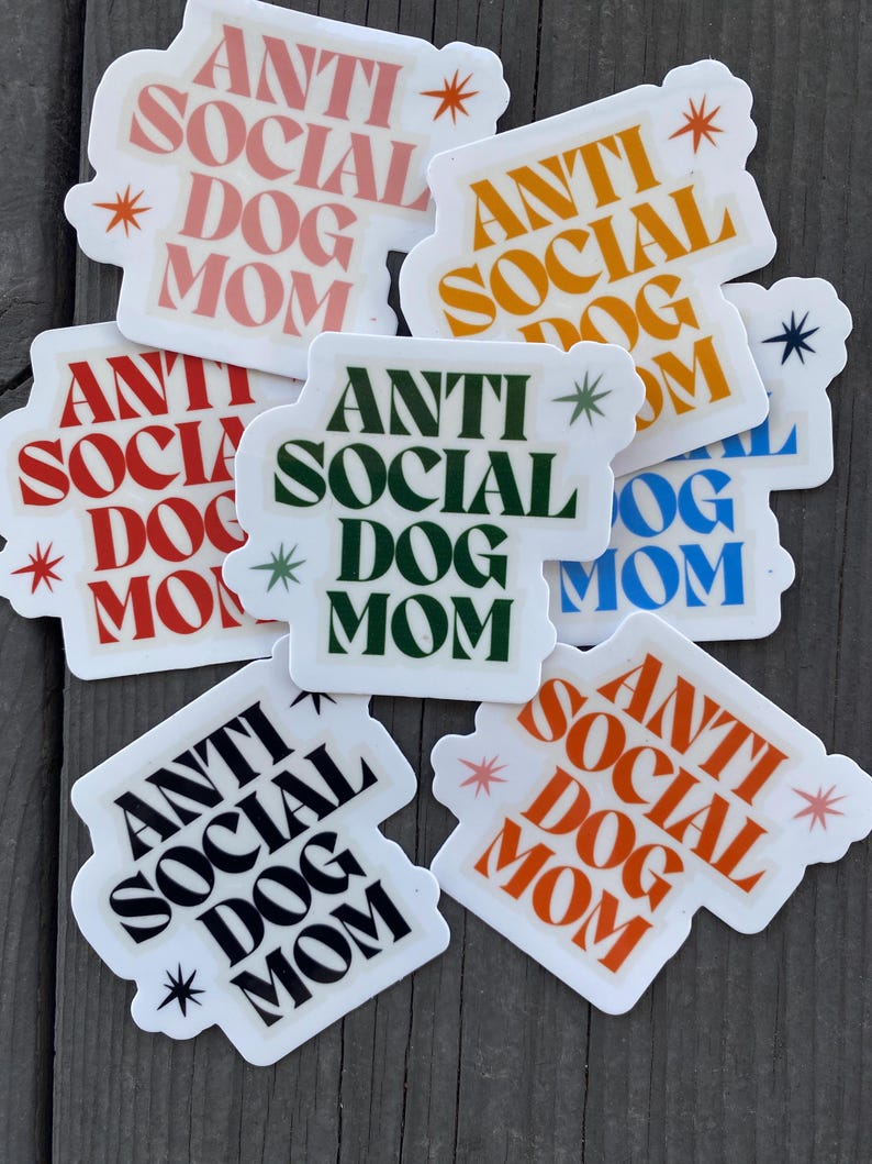 May include: Six white stickers with the text "Anti Social Dog Mom" in various colors and fonts. The stickers have a white background and are decorated with stars.