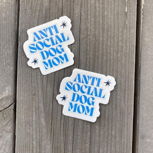 May include: Two white stickers with blue text that reads "Anti Social Dog Mom" with a star on either side of the text.