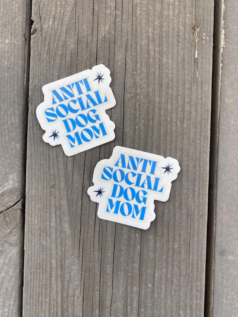 May include: Two white stickers with blue text that reads "Anti Social Dog Mom" with a star on either side of the text.