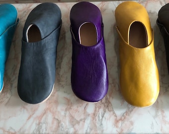 May include: Five pairs of leather slippers in different colors: teal, black, purple, yellow, and brown.