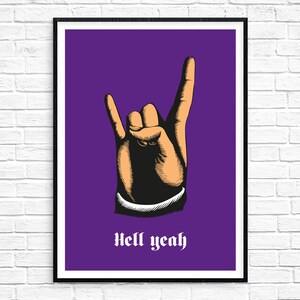 May include: A purple poster with a black frame featuring a hand making the rock and roll hand gesture. The text "Hell yeah" is printed in white below the hand.