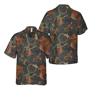 May include: A dark grey short-sleeved button-up shirt with a repeating pattern of brown and orange flying creatures with yellow rings and small green birds.