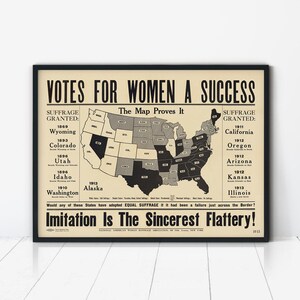 May include: A framed historical poster titled VOTES FOR WOMEN A SUCCESS. The center features a map of the United States with states shaded in black and grey, surrounded by lists of states that granted suffrage between 1869 and 1913.