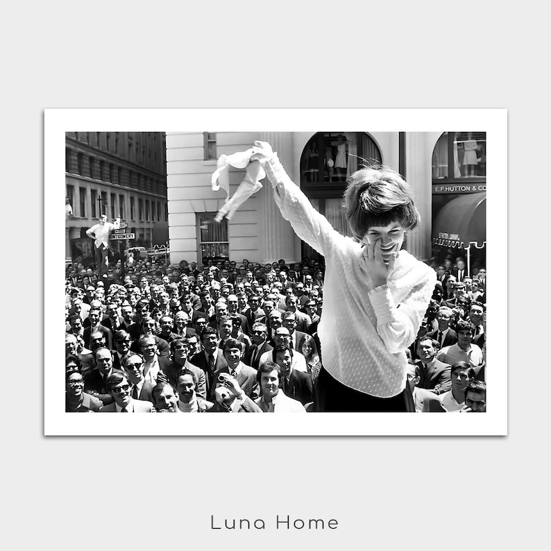 Puede incluir: Fotograf&iacute;a en blanco y negro de una mujer sonriendo y saludando a una multitud. Lleva una blusa blanca y una falda negra. La multitud est&aacute; compuesta por hombres con trajes. Impresi&oacute;n de Luna Home.