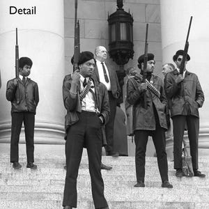 May include: Black and white photograph of a group of people, some holding rifles, standing on steps. The people are wearing black berets, jackets, and pants. The word "Detail" is in the top left corner.