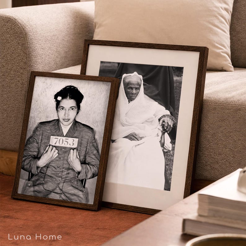 May include: Two framed black and white photographs in dark wood frames. The left frame shows a portrait of Rosa Parks holding a sign with the number 7053. The right frame displays a portrait of Harriet Tubman wearing a head covering and shawl.